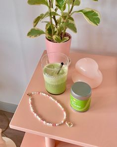 a potted plant sitting on top of a pink table next to a bracelet and other items