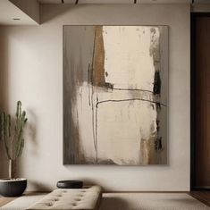 an abstract painting hangs on the wall above a bench in front of a potted cactus