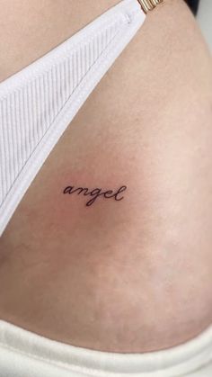 a woman's stomach with the word angel tattooed on her lower side ribcage