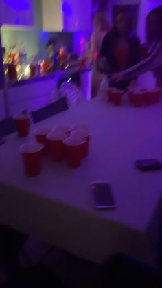 some people are sitting at a table with red cups and cell phones on the table