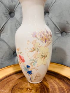 a white vase sitting on top of a wooden table