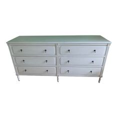 a white dresser with green top and drawers on the bottom drawer, against a white background