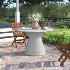 an outdoor table and chairs with flowers in the vase sitting on it's pedestal