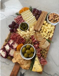 an assortment of cheeses, crackers and olives on a board