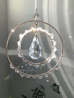 a clear crystal hanging from a metal ring with beads and crystals on it's sides