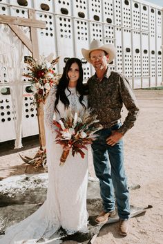 a man and woman standing next to each other in front of a white fence with flowers