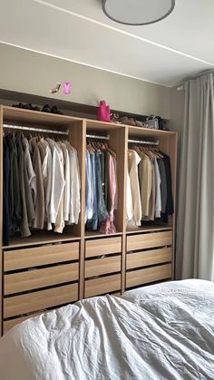 a bedroom with a bed, dresser and clothes hanging on the wall next to it