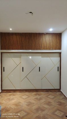 an empty room with wooden floors and white cabinets on the wall, in front of a wood paneled ceiling