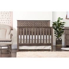 a baby crib in a room with a chair and rug on the floor next to it