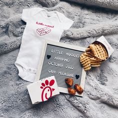 a baby's bodysuit, waffles and crackers on a blanket