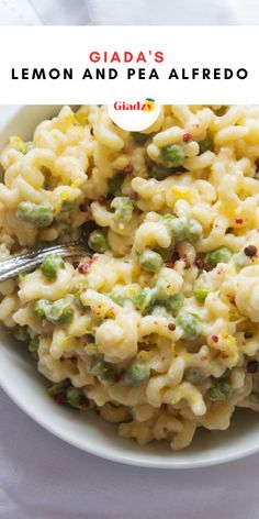 a white bowl filled with macaroni and peas on top of a white table cloth