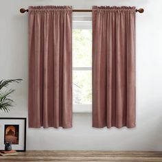 a window with pink curtains and a potted plant on the table next to it