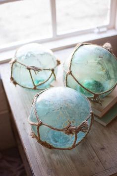 three glass balls sitting on top of a wooden table next to a book and window