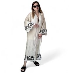 The Hittite printed  muslin kimono combines elegance and comfort seamlessly. Made from organic cotton, it offers an eco-friendly choice, while the OEKO-TEX certification ensures its health and environmental consciousness.  The kimono will elevate every moment with its sophistication, featuring unique patterns created using traditional woodblock printing and natural dyes. Suitable for both casual and special occasions, it effortlessly complements various outfits, adding a touch of style to your l Traditional Kimono For Spring Beach Cover-up, Embroidered Folk Kimono For Summer, Summer Folk Style Embroidered Kimono, Summer Embroidered Folk Kimono, Traditional Kimono For Beach Cover-up In Spring, Traditional Spring Kimono For Beach Cover-up, Traditional Embroidered Summer Kimono, Traditional Printed Kimono For Festivals, Long Beige Kimono For Festival