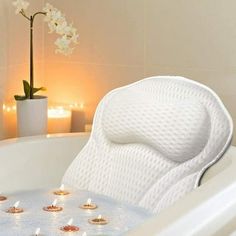 a white bath tub filled with lots of candles next to a flower pot and vase