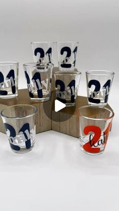 six shot glasses sitting on top of each other with numbers painted on the glass cups