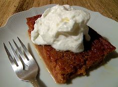 a piece of pie with whipped cream on top sits on a plate next to a fork