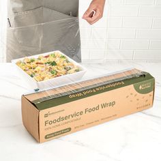 a box that has food in it on a table next to a person holding a knife