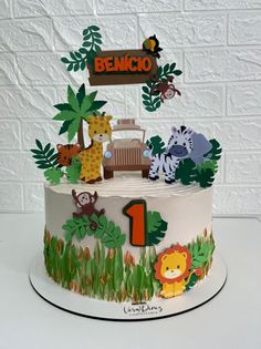 a birthday cake decorated with animals, trees and a number one on the top tier