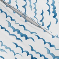 a pair of scissors sitting on top of a blue and white patterned sheet with wavy lines