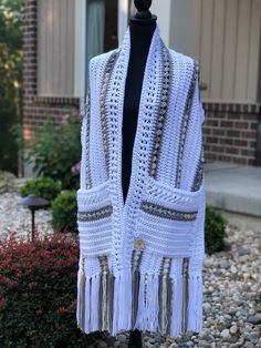 a white crocheted shawl with tassels hanging from it's sides