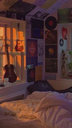 a bedroom with a guitar hanging from the ceiling next to a window and bed in front of it