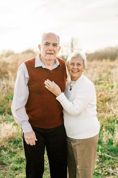 an older man and woman standing together in a field