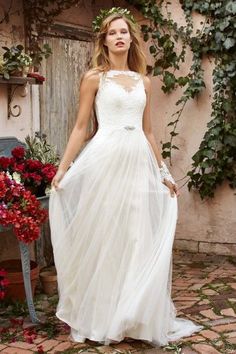 a woman wearing a white dress standing in front of flowers