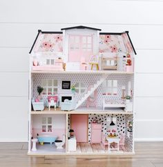 a doll house with pink furniture and accessories on the top floor in front of a white wall