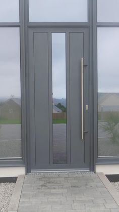 the front entrance to a building with large glass doors and brick walkway leading up to it