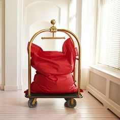 a large red bag sitting on top of a metal cart in a room next to a window