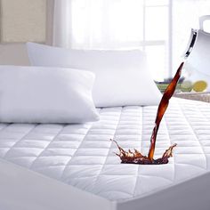 a bed that has been made with white pillows and a brown liquid pouring out of it