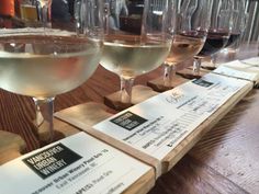 several glasses of wine sitting on top of a wooden table with menus and drinks in front of them