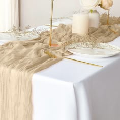 a table topped with plates and flowers on top of a white table cloth covered table