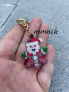 a hand holding a tiny beaded keychain with a santa clause on it