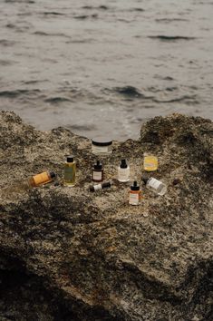 an assortment of bottles sitting on top of a rock next to the ocean