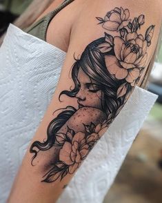 a woman's arm with flowers on it and a girl in the middle of her arm