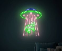 a neon sign in the shape of an alien ship with a cow on it's back