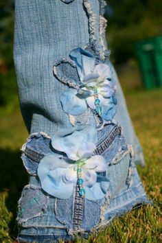 a pair of blue jeans with flowers on them sitting in the middle of some grass