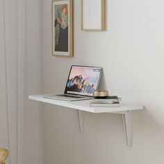 a laptop computer sitting on top of a white shelf