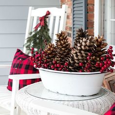 a white bowl filled with pine cones sitting on top of a table next to a window