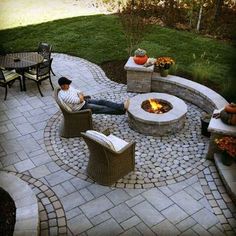 a man sitting in a chair next to a fire pit on top of a patio