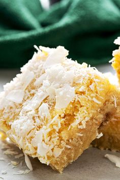 two pieces of coconut cake sitting on top of a white tablecloth next to a green napkin