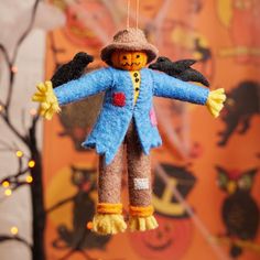 an ornament made to look like a scarecrow hanging from a string with lights in the background