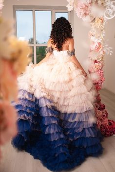 a woman in a multicolored dress is sitting on the floor near a flower arch