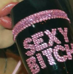 a close up of a person holding a black cup with pink glitters on it