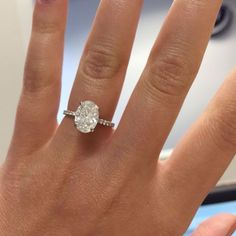 a woman's hand with a diamond ring on top of her finger and an engagement band