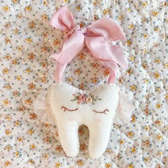 a tooth shaped pillow with a pink bow on it's head sitting on a bed