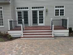 a brick patio with steps leading up to the front door and two doors on each side