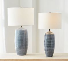 two lamps sitting on top of a table next to each other, one with a white shade